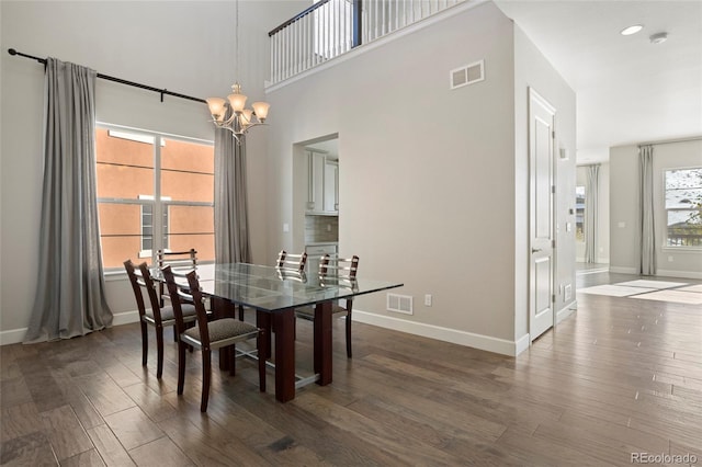 dining room with a towering ceiling, a chandelier, and dark hardwood / wood-style flooring