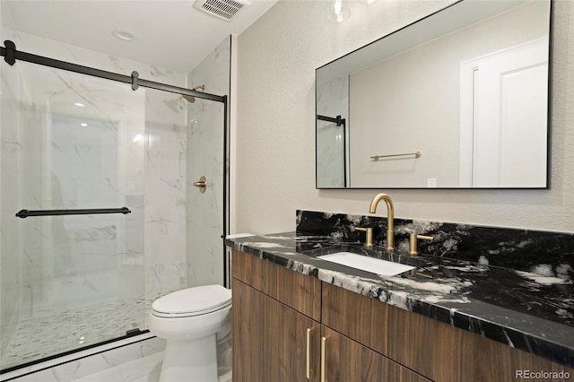 bathroom with a shower with door, vanity, and toilet