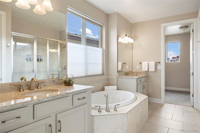full bathroom featuring a stall shower, a garden tub, two vanities, tile patterned floors, and baseboards
