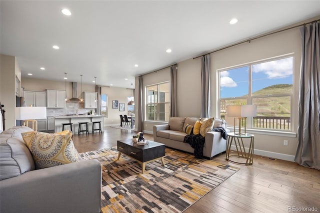 living area featuring plenty of natural light, wood finished floors, baseboards, and recessed lighting