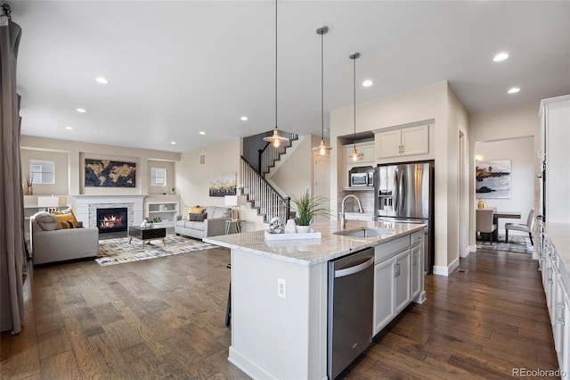 kitchen with appliances with stainless steel finishes, a sink, dark wood-style flooring, open floor plan, and recessed lighting
