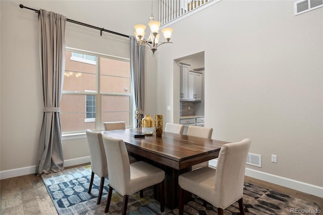 dining space with baseboards, a chandelier, and wood finished floors