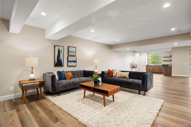 living area featuring recessed lighting, baseboards, light wood finished floors, and wet bar