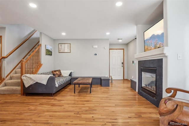 living room with a tiled fireplace, stairway, visible vents, light wood-style floors, and recessed lighting