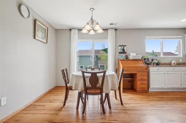 dining room with a chandelier, baseboards, visible vents, and light wood-style floors