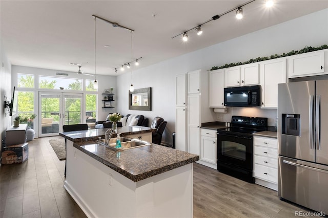 kitchen featuring sink, black appliances, white cabinets, and a center island with sink