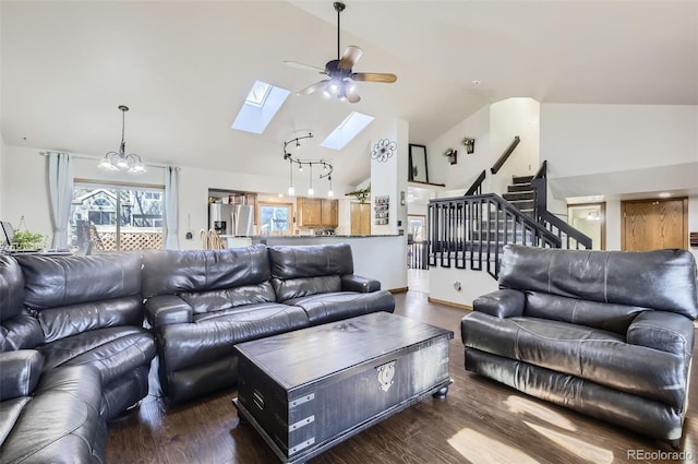 living room with dark hardwood / wood-style flooring, ceiling fan with notable chandelier, a skylight, and high vaulted ceiling