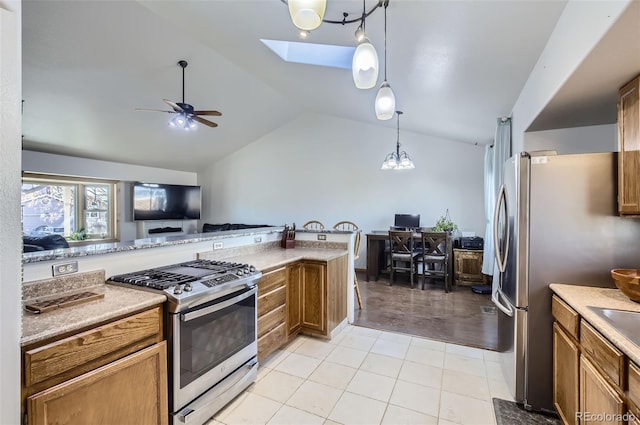 kitchen with stainless steel appliances, lofted ceiling with skylight, ceiling fan, pendant lighting, and light hardwood / wood-style floors