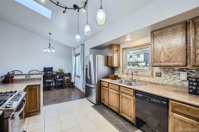 kitchen with backsplash, sink, stainless steel appliances, and decorative light fixtures