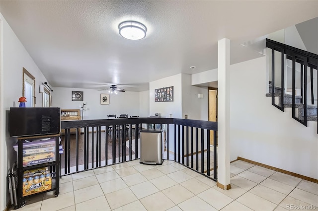 hall with a textured ceiling and light tile patterned flooring