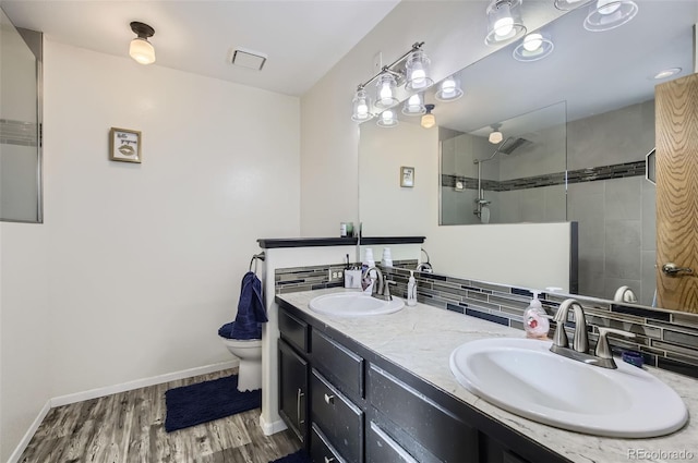 bathroom featuring tasteful backsplash, vanity, tiled shower, hardwood / wood-style floors, and toilet