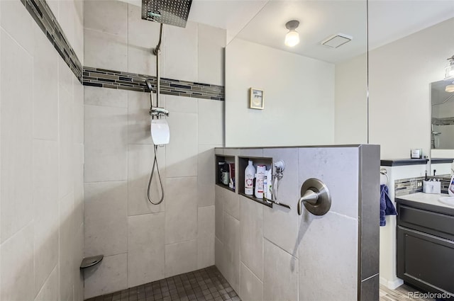 bathroom featuring tiled shower and vanity