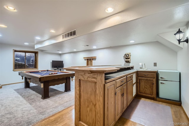 kitchen with kitchen peninsula, vaulted ceiling, light hardwood / wood-style flooring, and billiards