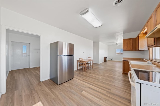 kitchen with white range oven, ceiling fan, light hardwood / wood-style floors, stainless steel refrigerator, and sink