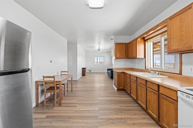 kitchen with plenty of natural light, sink, light hardwood / wood-style floors, and stainless steel fridge