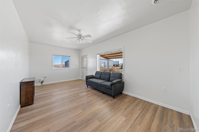 living area with ceiling fan, light wood-type flooring, and a wealth of natural light