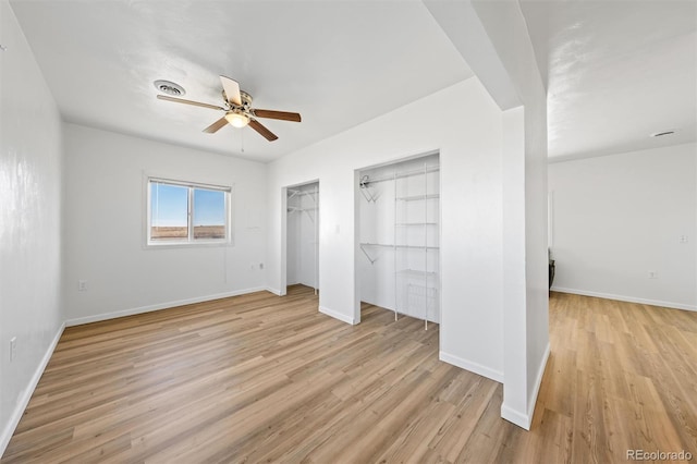 unfurnished bedroom featuring light hardwood / wood-style flooring, ceiling fan, and multiple closets