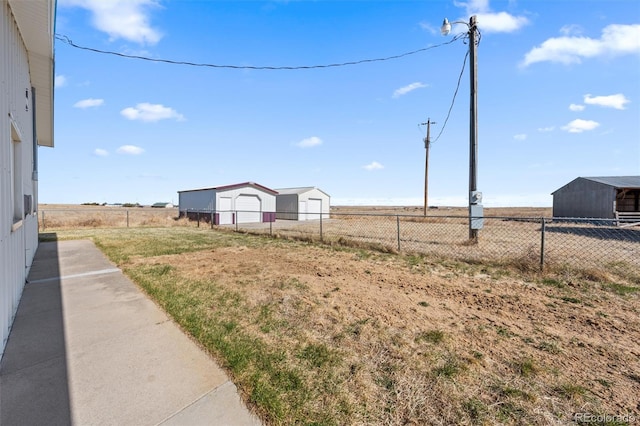 view of yard with a garage, a rural view, and an outdoor structure