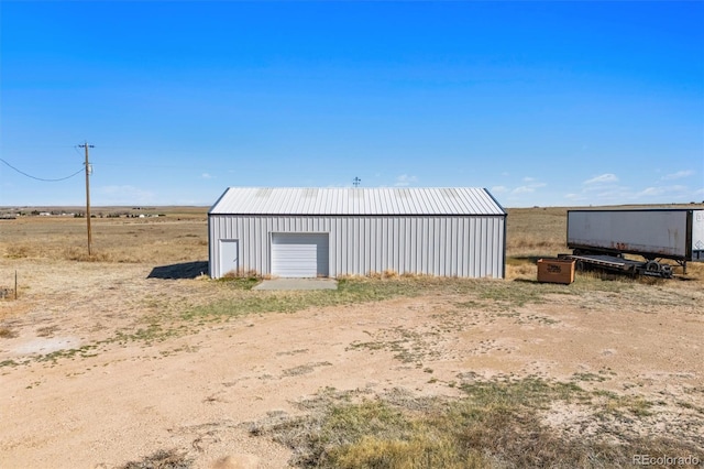 view of outdoor structure featuring a rural view and a garage