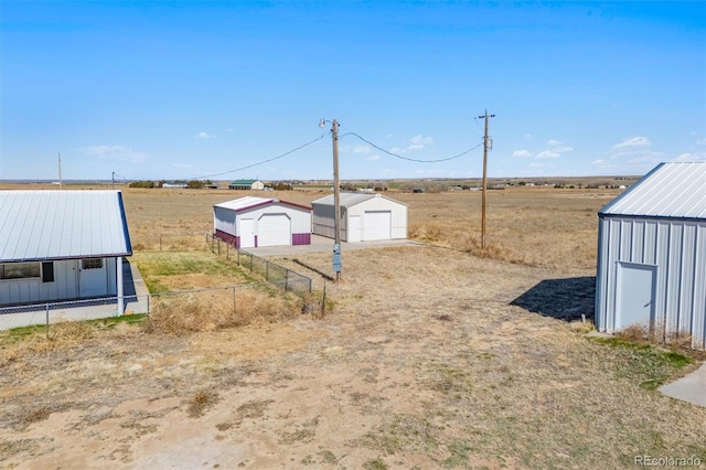 view of yard with a garage, a rural view, and an outdoor structure