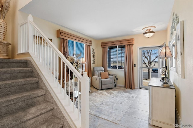 entrance foyer featuring light tile patterned flooring, stairway, and baseboards