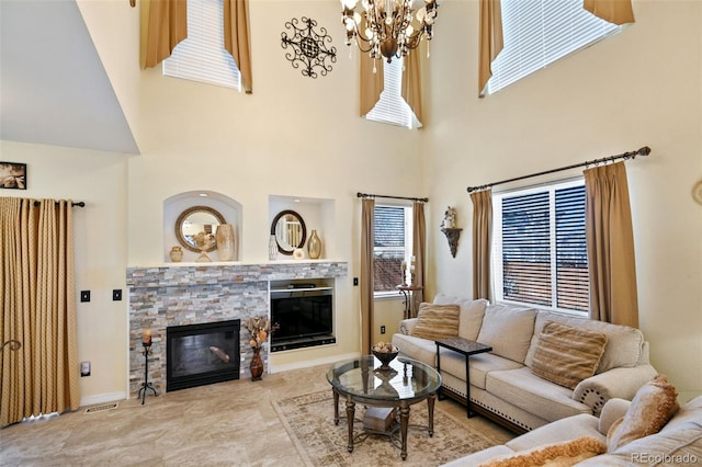 living room featuring a stone fireplace, a notable chandelier, visible vents, and baseboards