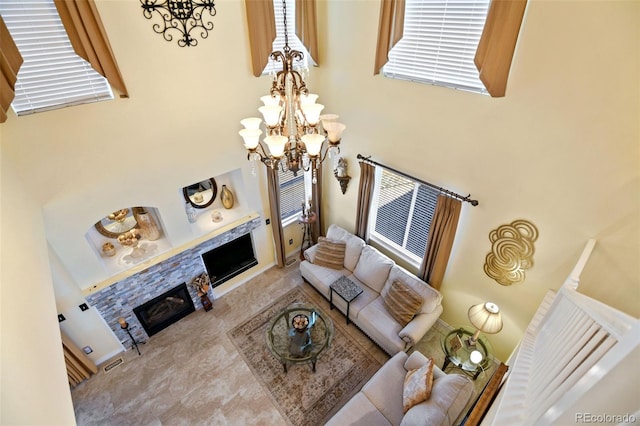 living room with visible vents, a fireplace, a high ceiling, and an inviting chandelier