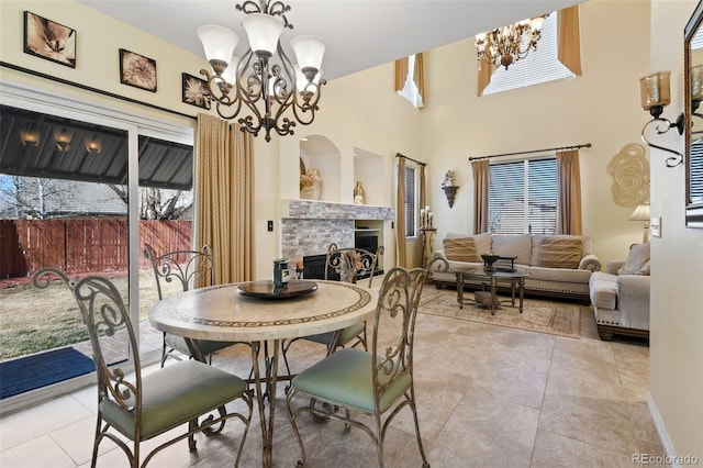 dining space featuring an inviting chandelier, a towering ceiling, a fireplace, and tile patterned floors