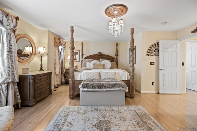 bedroom featuring an inviting chandelier, light wood-style flooring, and baseboards