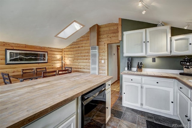 kitchen featuring white cabinets, lofted ceiling with skylight, log walls, and beverage cooler