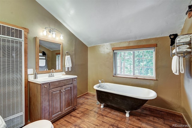 bathroom with lofted ceiling, a bathtub, hardwood / wood-style flooring, toilet, and vanity