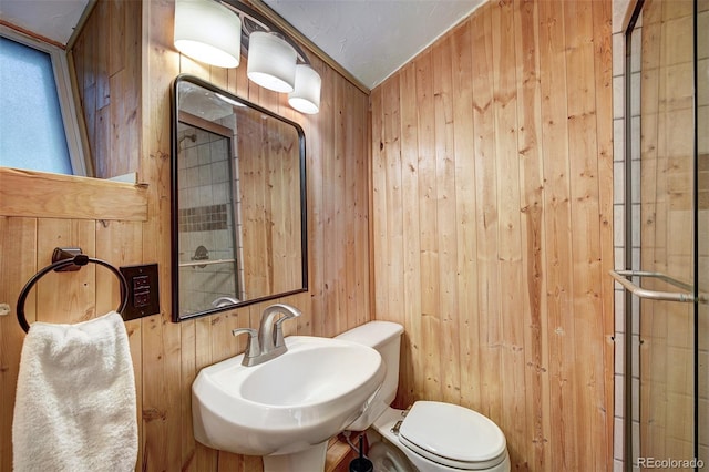 bathroom with sink, toilet, and wood walls