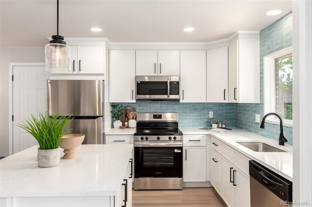1011 Yeager Dr, Longmont, CO 80501 - kitchen featuring stainless steel appliances, white cabinets, a kitchen island, pendant lighting, and light wood-type flooring