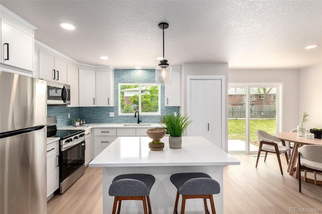 1011 Yeager Dr, Longmont, CO 80501 - kitchen with stainless steel appliances, a breakfast bar, tasteful backsplash, light wood-type flooring, and light countertops