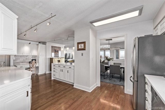 kitchen featuring white cabinetry, stainless steel fridge, dark hardwood / wood-style flooring, and decorative light fixtures