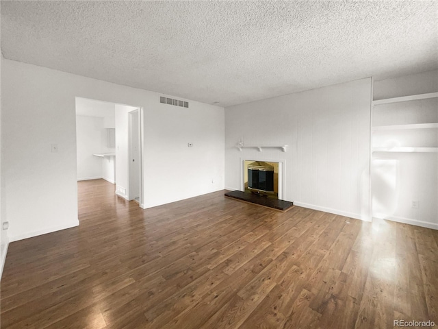 unfurnished living room with dark wood-type flooring and a textured ceiling