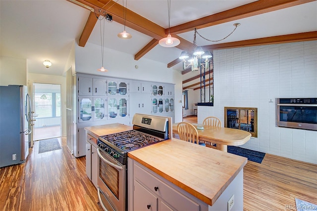 8300 W 67th Ave, Arvada, CO 80004 - kitchen with stainless steel appliances, light wood finished floors, a chandelier, wooden counters, and a fireplace