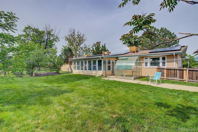 8300 W 67th Ave, Arvada, CO 80004 - back of property with an exterior structure, a sunroom, roof mounted solar panels, and an outbuilding