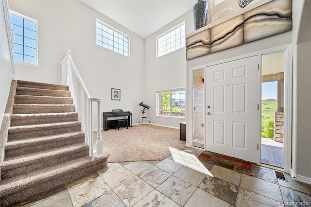 22227 E Hinsdale Ave, Aurora, CO 80016 - carpeted foyer entrance featuring baseboards, stairs, a towering ceiling, and stone tile floors
