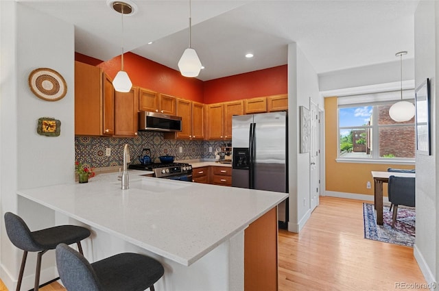 7828 W 54th Ave, Arvada, CO 80002 - kitchen with stainless steel appliances, a peninsula, baseboards, light wood-type flooring, and decorative backsplash