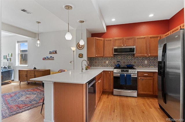 7828 W 54th Ave, Arvada, CO 80002 - kitchen featuring stainless steel appliances, a peninsula, a sink, light wood finished floors, and light countertops