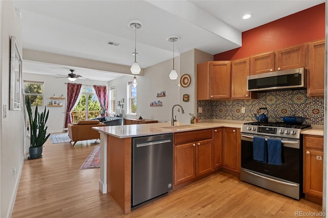 7828 W 54th Ave, Arvada, CO 80002 - kitchen with stainless steel appliances, a sink, a peninsula, light wood-style floors, and light countertops
