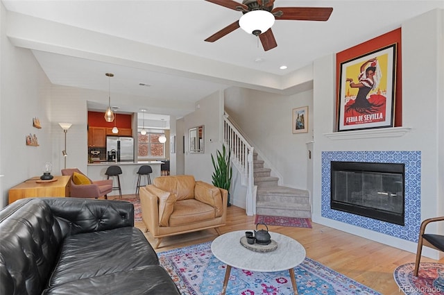 7828 W 54th Ave, Arvada, CO 80002 - living area with light wood finished floors, a ceiling fan, stairway, a tile fireplace, and recessed lighting