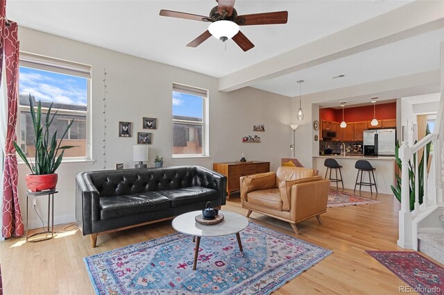 7828 W 54th Ave, Arvada, CO 80002 - living area with light wood-style floors, healthy amount of natural light, a ceiling fan, and baseboards