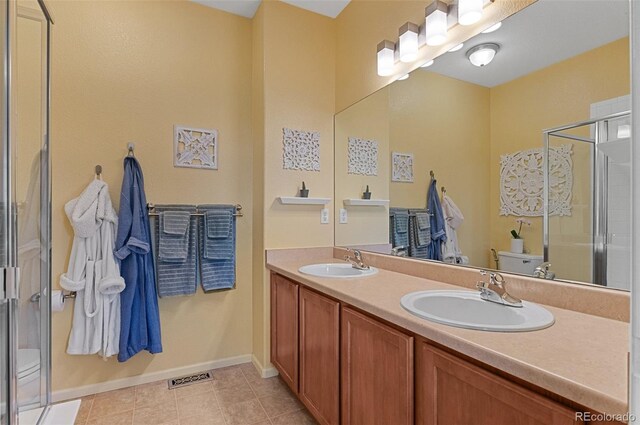 7828 W 54th Ave, Arvada, CO 80002 - bathroom featuring toilet, double vanity, a stall shower, baseboards, and tile patterned floors