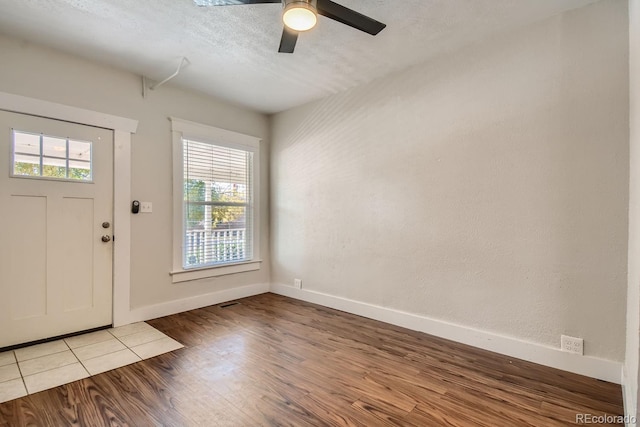 foyer with ceiling fan, a textured ceiling, and light hardwood / wood-style flooring