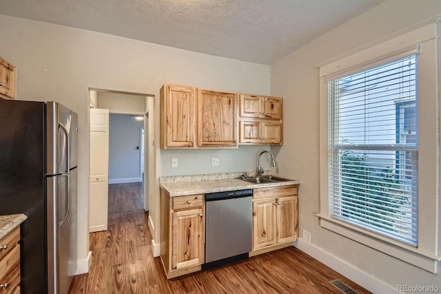 kitchen with a textured ceiling, wood-type flooring, sink, and stainless steel appliances