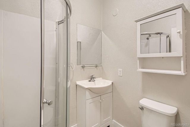 bathroom with a shower with shower door, vanity, and toilet