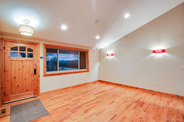 interior space with lofted ceiling, wood finished floors, baseboards, and visible vents