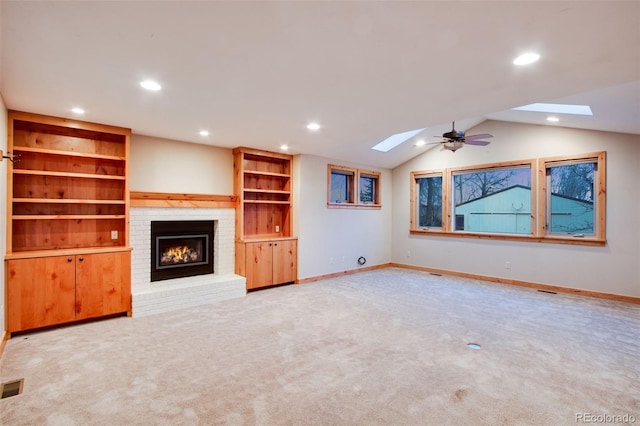 unfurnished living room featuring baseboards, carpet floors, vaulted ceiling with skylight, recessed lighting, and a brick fireplace